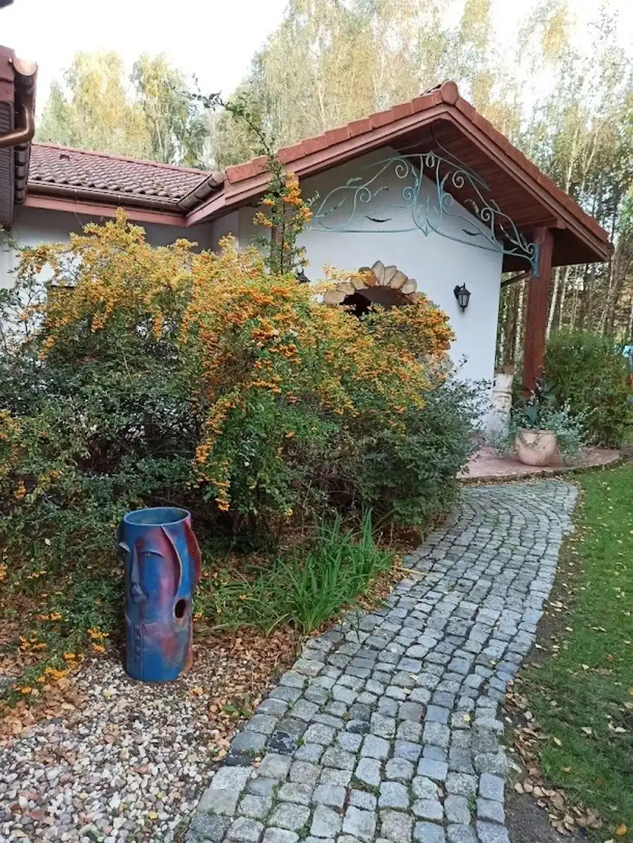 Urokliwe wejście do budynku z ozdobnymi krzewami