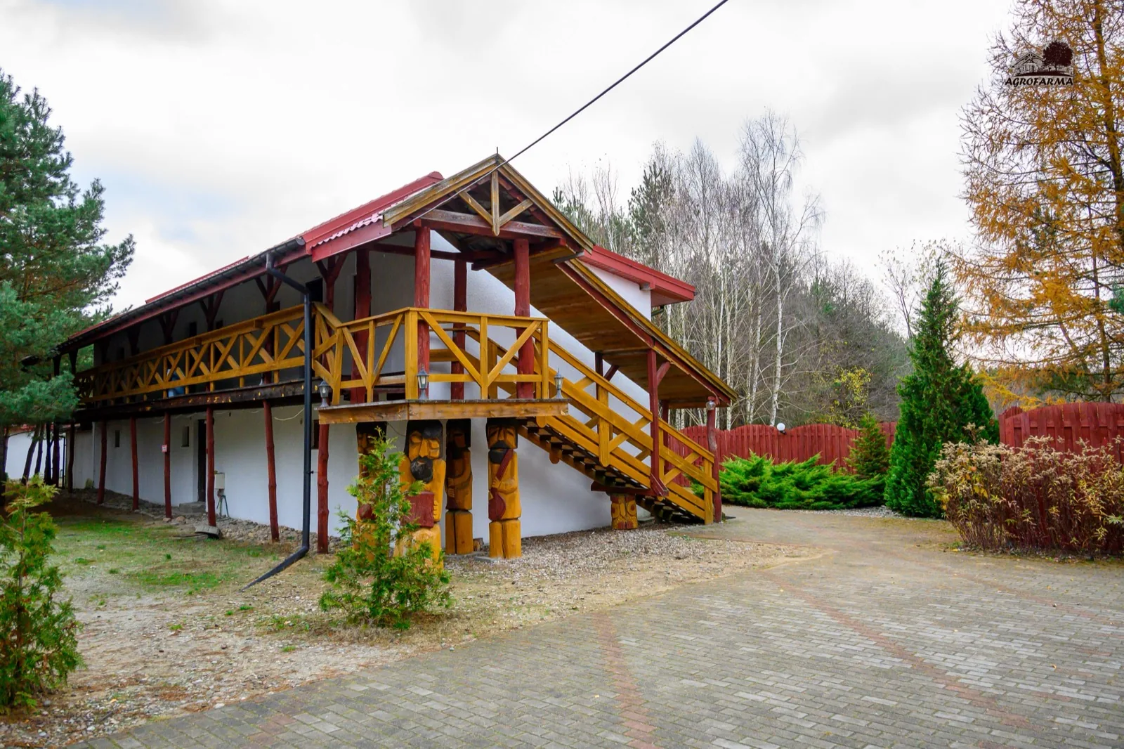 Budynek z drewnianym balkonem i schodami — AgroFarma jesienią