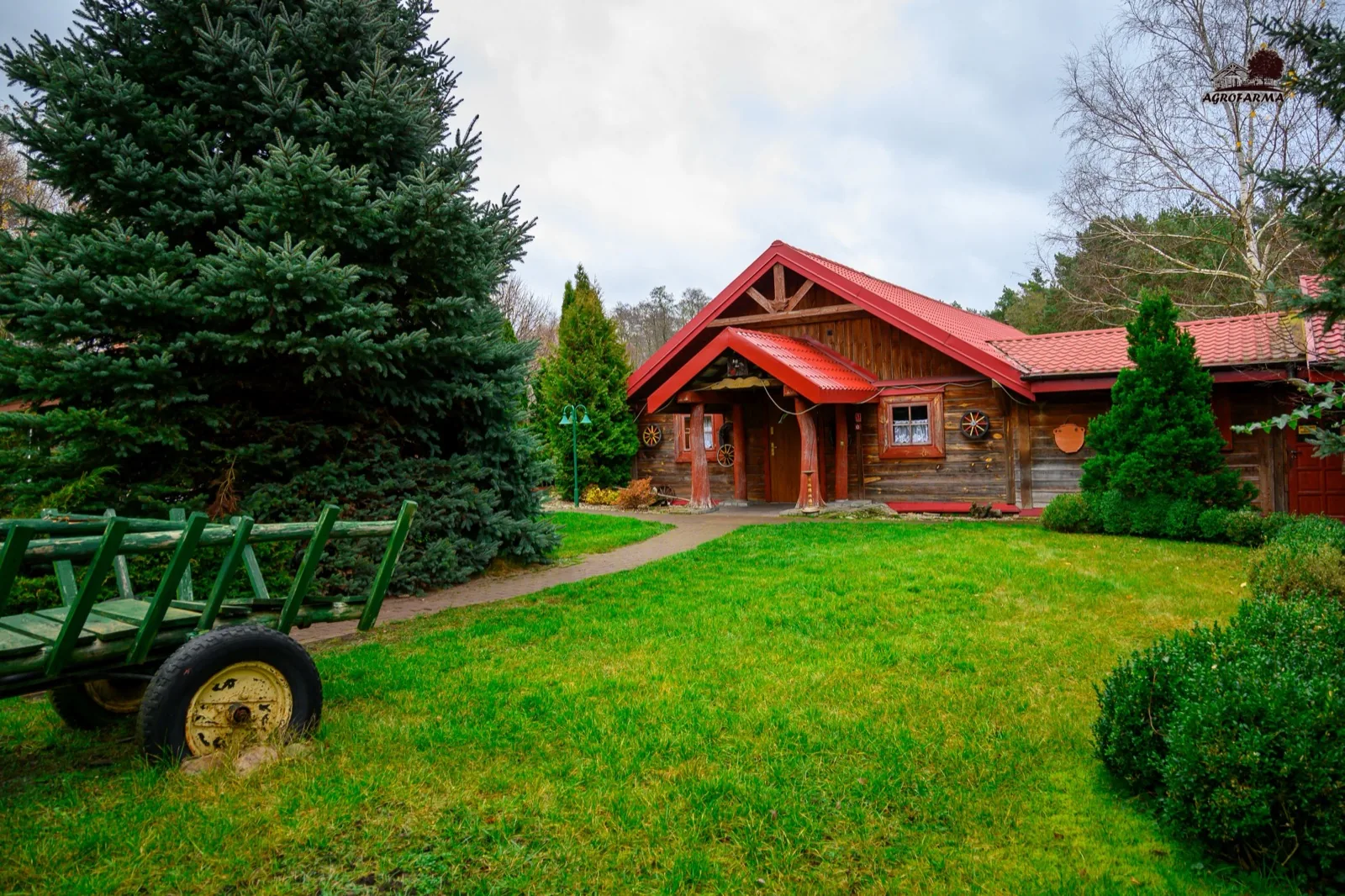 Drewniany domek noclegowy z zabytkowym wozem w ogrodzie