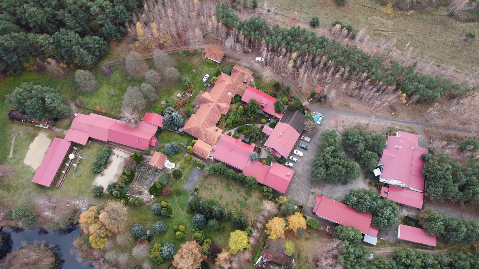 Widok z drona na ośrodek AgroFarma jesienią — budynki wśród kolorowych drzew